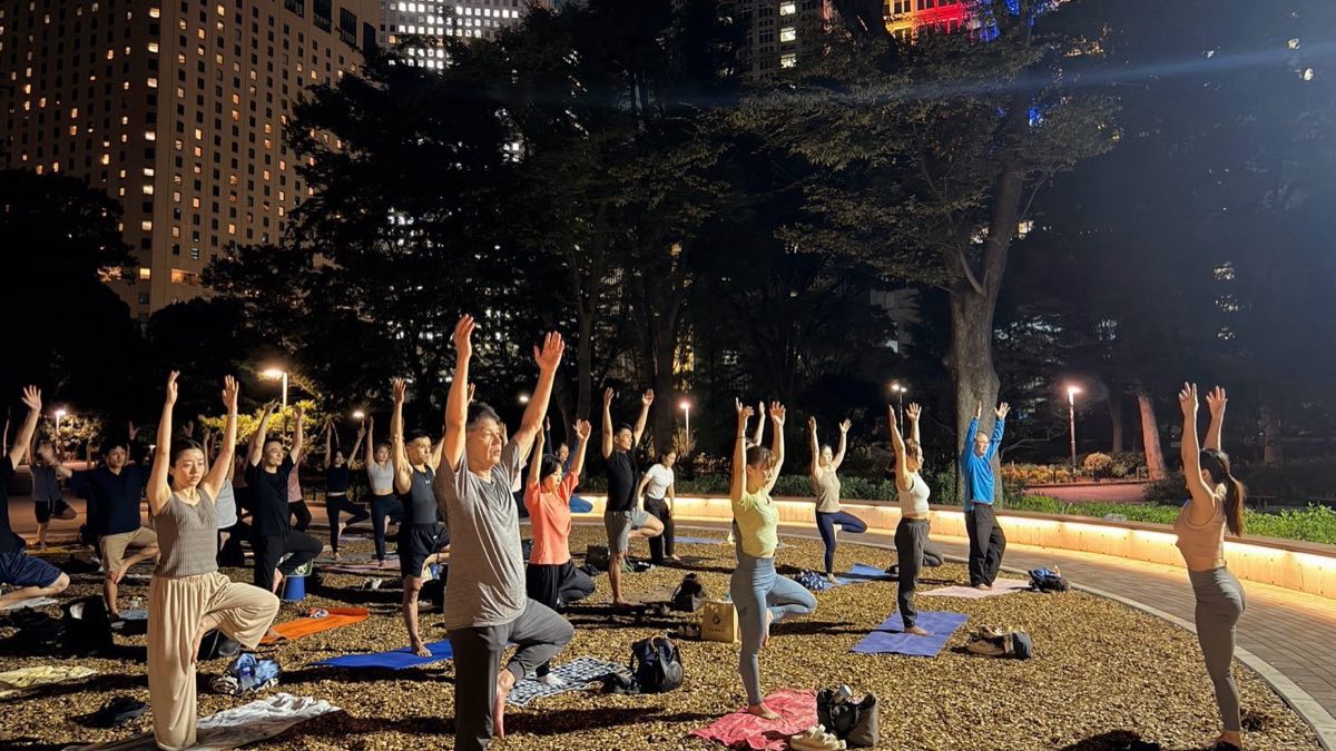 夜の公園でのクラス。都心のビルを背に、参加者が両手を上げているところ
